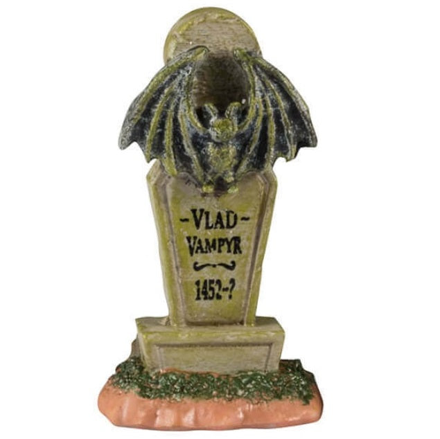 Resin village accents for a Lemax display. Designed to look like three headstones. One has a bat statue on it and it reads "Vlad Vampyr 1452-?" The next one is shaped like a cat and reads "RIP Miss Kitty aka Crazy Cat Lady." There are black cats on it. The next one features a skull with snakes coming out of it and a bunch of red candles lit at the base.