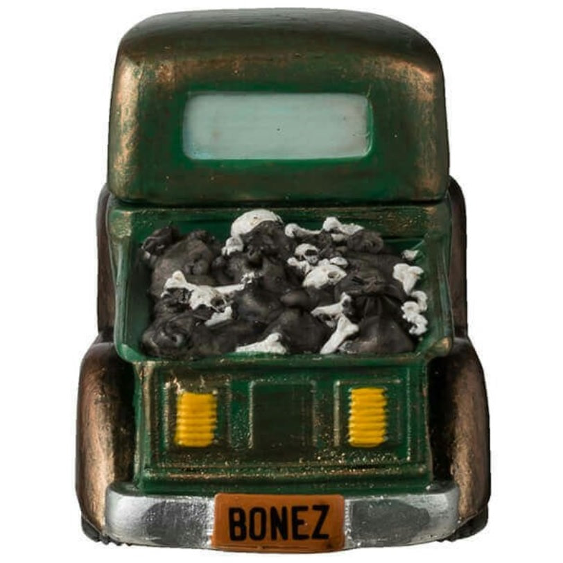 Resin figurine for a Lemax display. Designed to look like a rusty, green truck driven by a skeleton. There's a lot of garbage in the truck bed. The license plate is orange and reads "BONEZ."