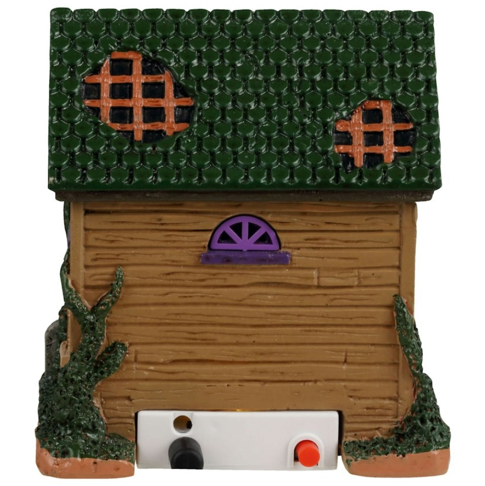 Resin building for a Lemax display. Designed to look like a rundown house. Part of the roof is missing and the windows are boarded up. There's a woman wearing a light blue dress in the doorway handing out candy. There's a black cat and two carved pumpkins and a tombstone that reads RIP.