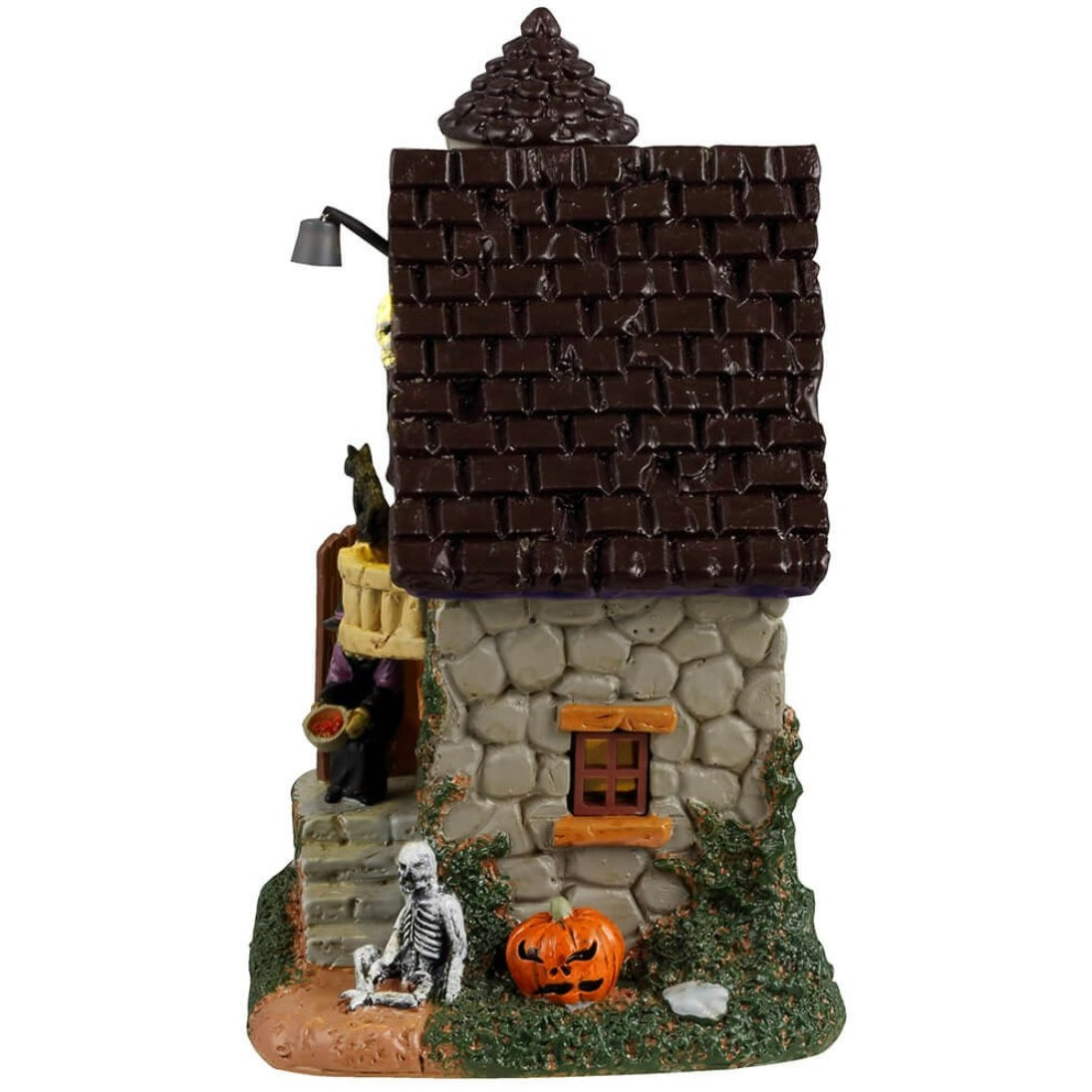 Resin building for a Lemax display. Designed to look like a stone house with moss growing on the side. There's a witch handing out candy at the front door and a skeleton sitting on the ground next to a pumpkin.