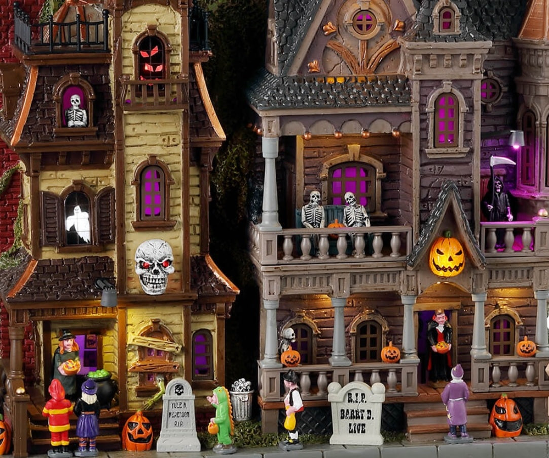 Resin lighted building for a Lemax display. Designed to look like a two Victorian-era style mansions standing next to each other. The one on the left is run down with boarded windows. The one on the right looks bright and regal. There are kids trick or treating at both homes and monsters, skeletons and ghosts in the windows.