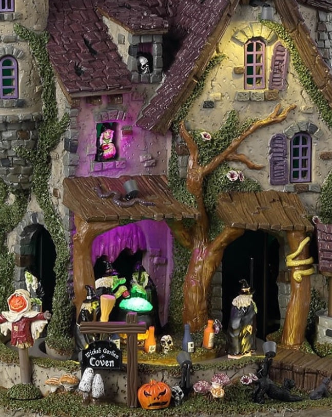 Resin lighted building for a Lemax display. Looks like a cottage with a moss covered tower. There are witches flying above and monsters and witches and a scarecrow and pumpkins.