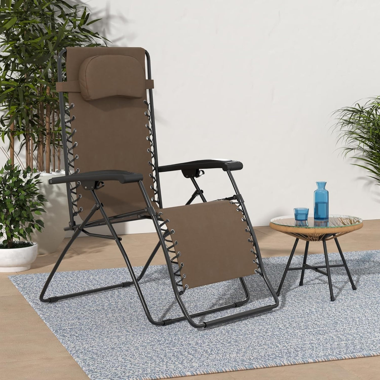 This image shows the brown colored Zero Gravity chair on a backyard patio.