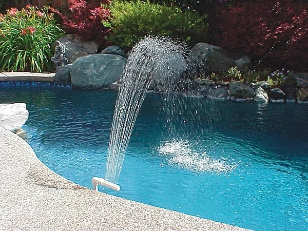 White waterfall fountain that attaches to your pool's water return fitting. This image shows the fountain in use on the side of an inground pool.