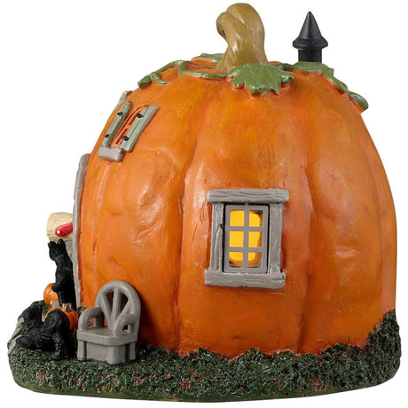 Resin village accent for a Lemax display. Designed to look like a cabin made out of a pumpkin. There are black cats and pumpkin accents. There's also a gray chair outside near the front door.