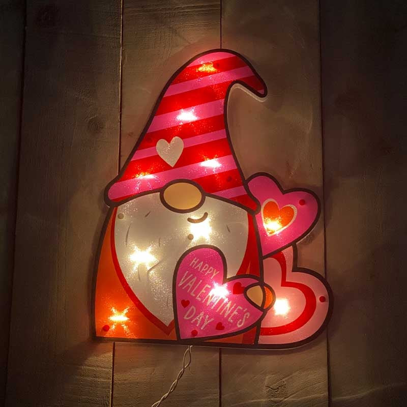 Lighted decoration shaped like a gnome wearing a tall red and pink striped hat. He's holding a heart that reads "HAPPY VALENTINE'S DAY!"