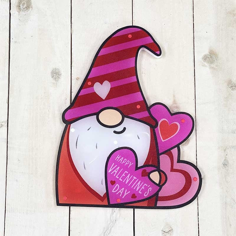 Lighted decoration shaped like a gnome wearing a tall red and pink striped hat. He's holding a heart that reads "HAPPY VALENTINE'S DAY!"