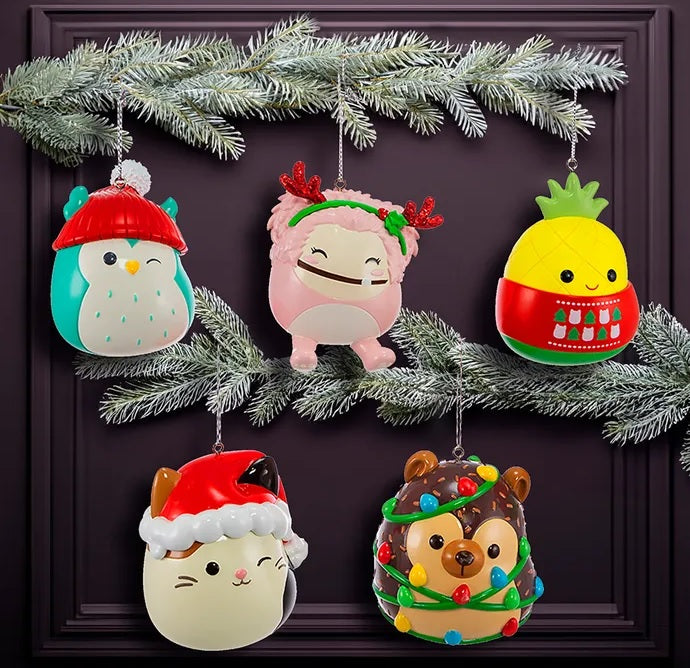 Blow mold Squishmallow ornament. One ornament is Winston the teal owl. One ornament is Cam the calico cat. One ornament is Hans the brown hedgehog. One ornament is Maui the yellow pineapple. One ornament is Brina the pink bigfoot.