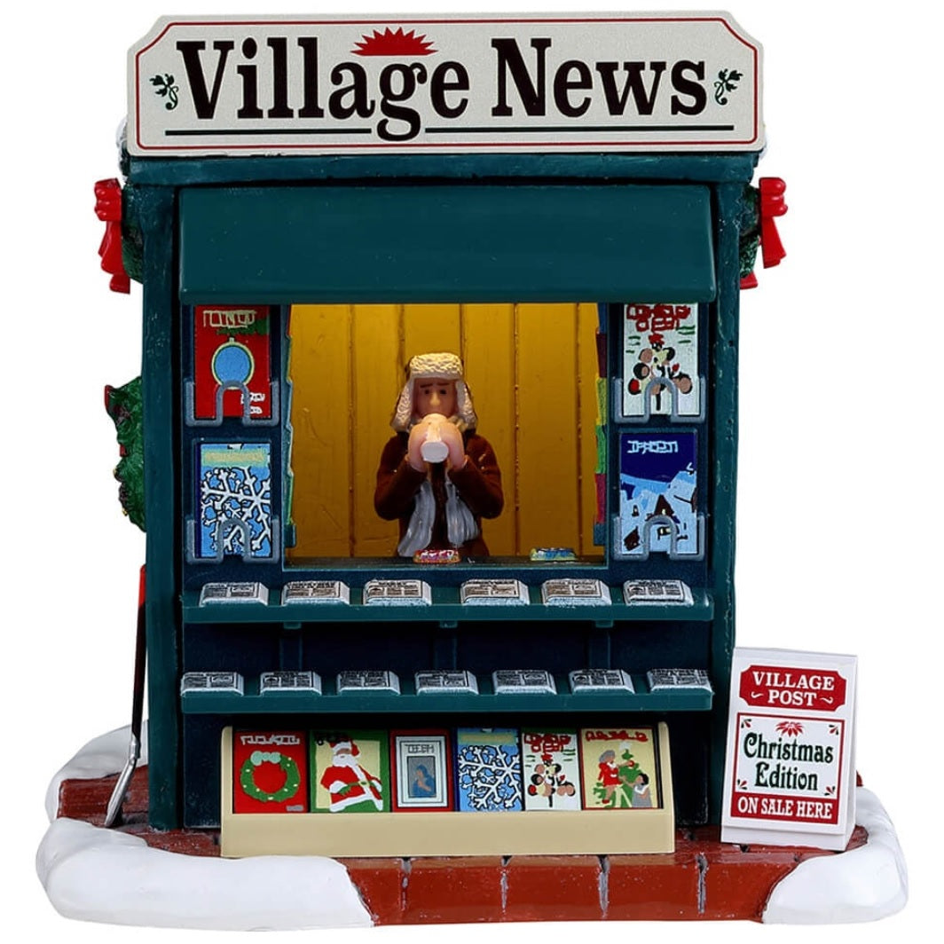 Resin village accent for a Lemax display. Designed to look like a newspaper stand decorated for Christmas. The vendor inside is wearing a winter hat, scarf and coat and is drinking from a white cup.