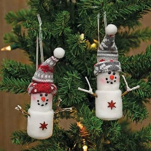 Marshmallow snowman ornament. One snowman is wearing a red knitted hat. One snowman is wearing a gray knitted hat. Both feature details like smiling faces with rosy cheeks, twig arms and snowflake charms.