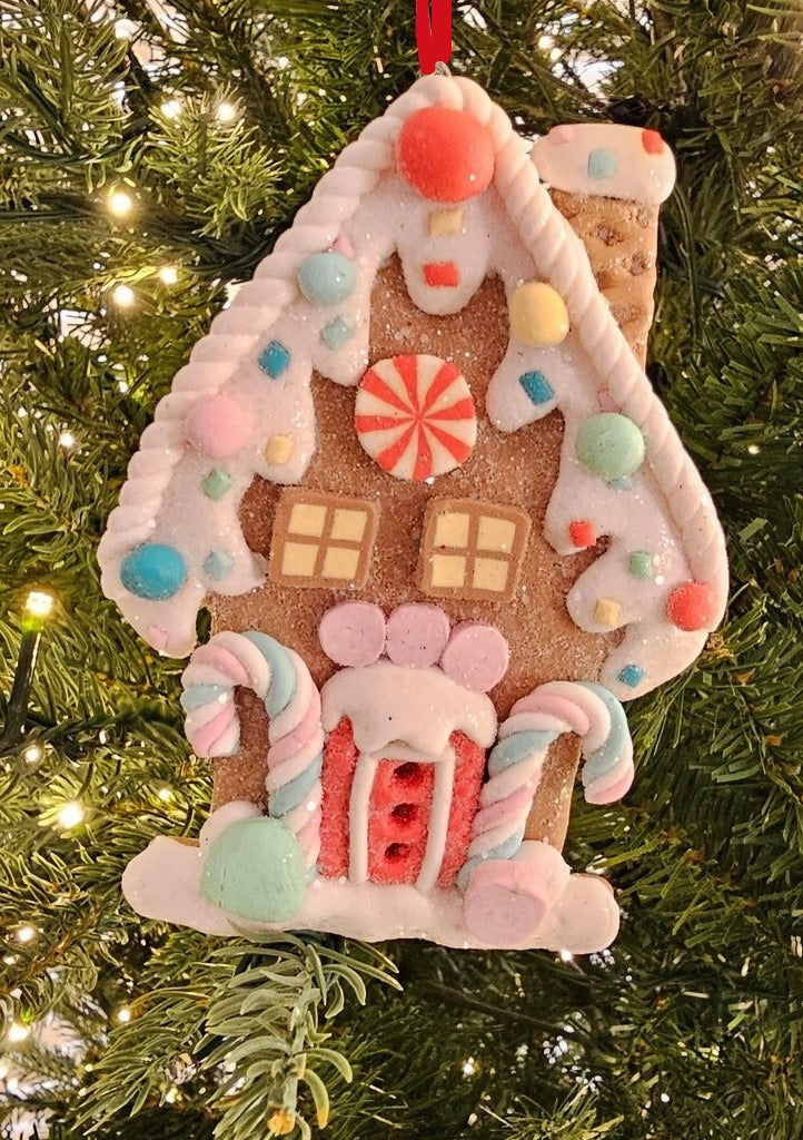 One gingerbread house is teal with a holly leaf accent. One gingerbread house is pink with a wreath accent. One gingerbread house is brown with a peppermint accent. Each ornament features faux candy canes, frosting and gum drop accents.