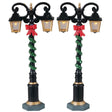 Plastic village accessories for a Lemax display. Designed to look like two regal lampposts wrapped with green tinsel and red bows.