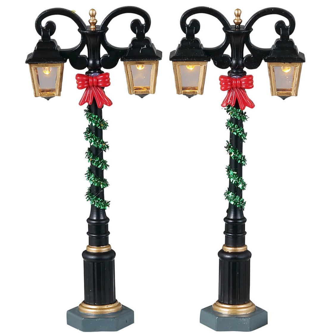 Plastic village accessories for a Lemax display. Designed to look like two regal lampposts wrapped with green tinsel and red bows.