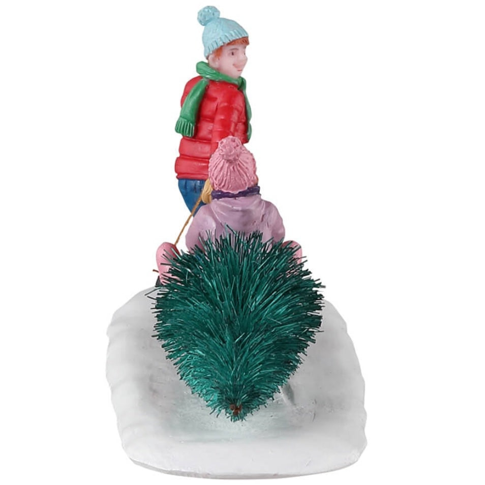 Resin village accent for a Lemax display. Designed to look like a young boy dragging a sled with a young girl and a little dog on it. The sled is also dragging a tree.