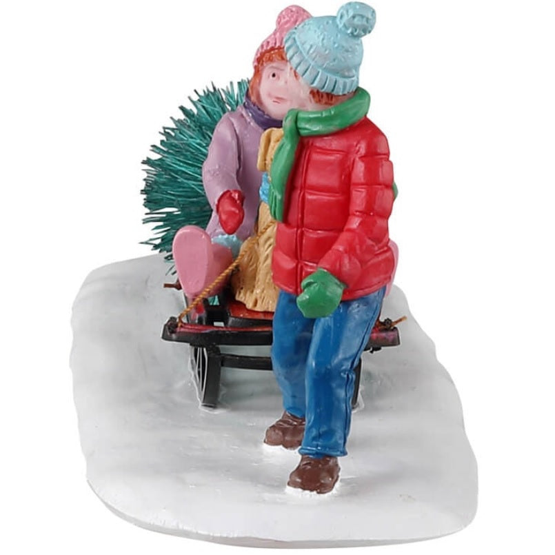 Resin village accent for a Lemax display. Designed to look like a young boy dragging a sled with a young girl and a little dog on it. The sled is also dragging a tree.