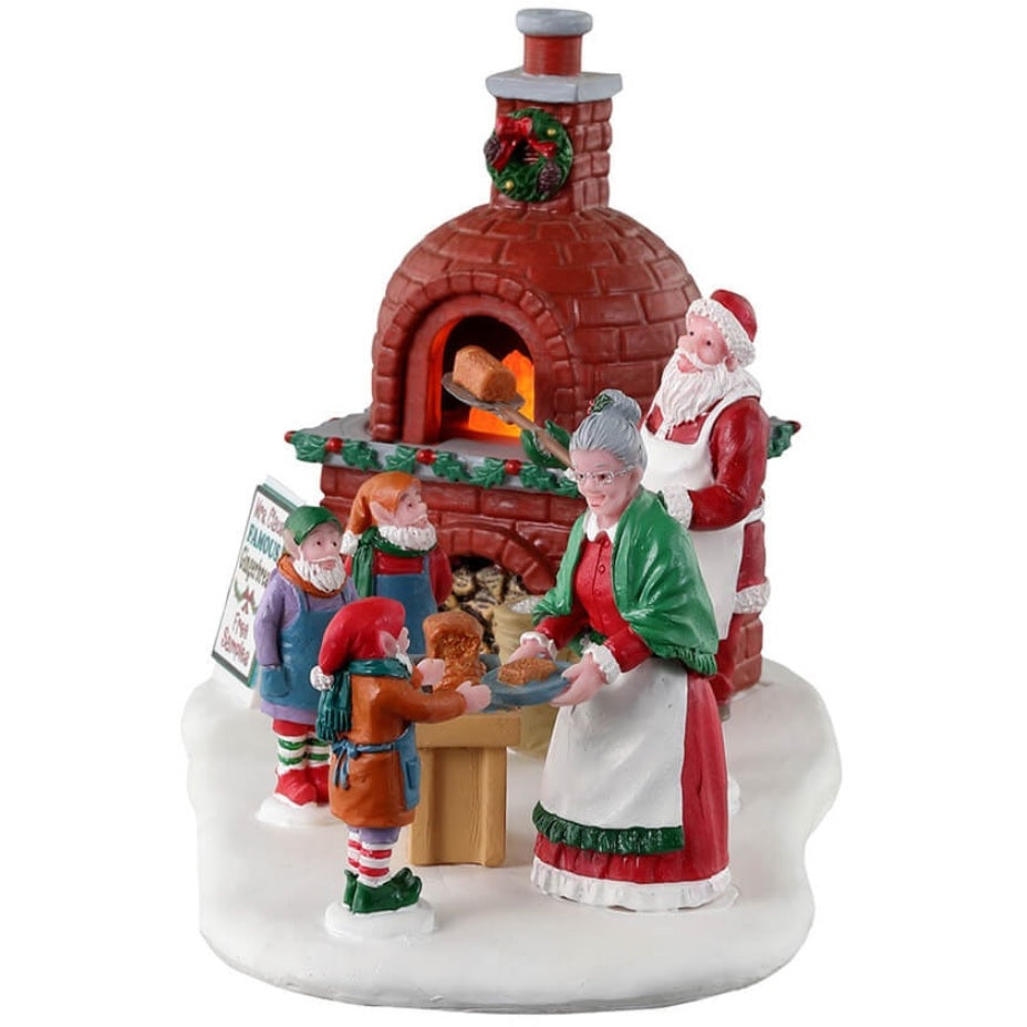 Resin village accent for a Lemax display. Designed to look like Santa and Mrs. Claus cooking gingerbread in a wood-fired oven. There are three elves helping.