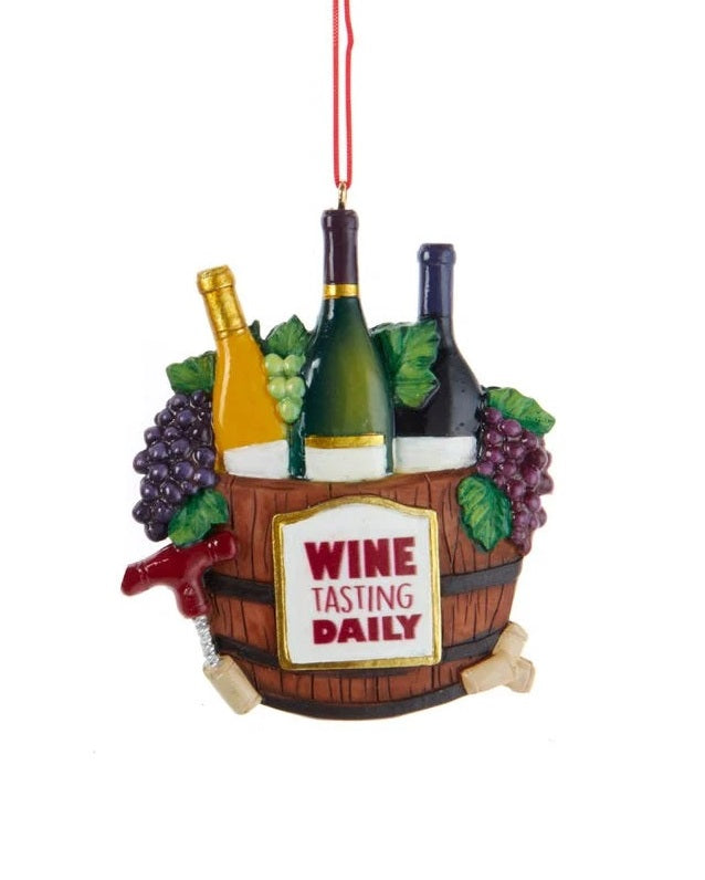 Wine-themed ornament. There are two options. One ornament features a barrel and reads "Veni Vidi Vino I cam I Saw I wined." One ornament features a bucket of wine bottles and reads "Wine Tasting Daily." Each ornament is decorated with grapes, wine glasses and wine bottles.