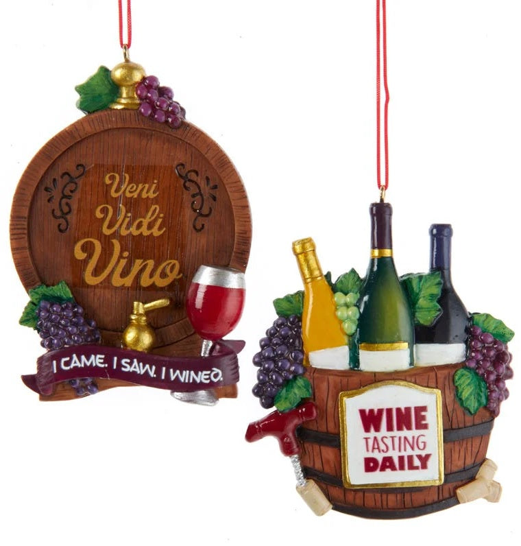 Wine-themed ornament. There are two options. One ornament features a barrel and reads "Veni Vidi Vino I cam I Saw I wined." One ornament features a bucket of wine bottles and reads "Wine Tasting Daily." Each ornament is decorated with grapes, wine glasses and wine bottles.