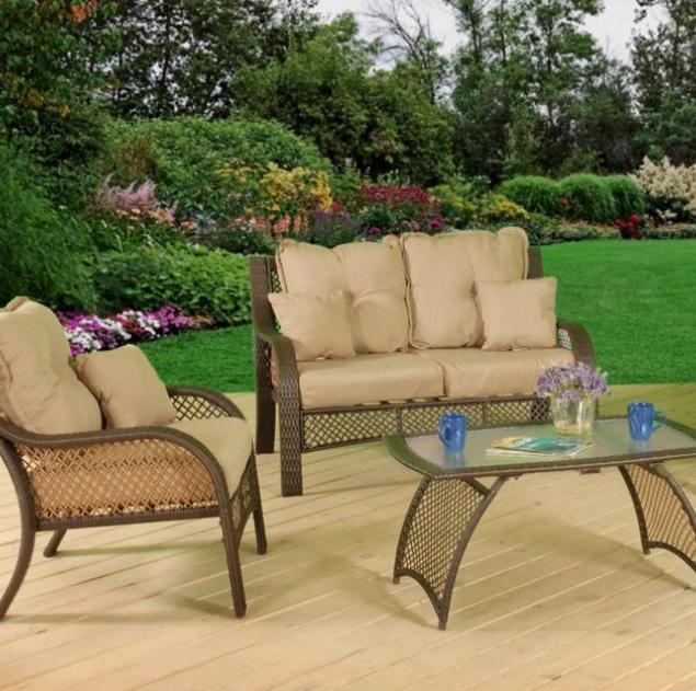 Patio furniture set on a stone patio. The frames are dark brown and the cushions are an orange-ish, tan color.