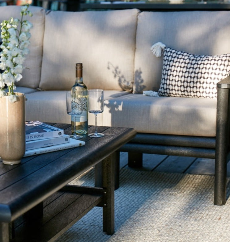 A close up of an outdoor couch and a coffee table with wine glasses on top