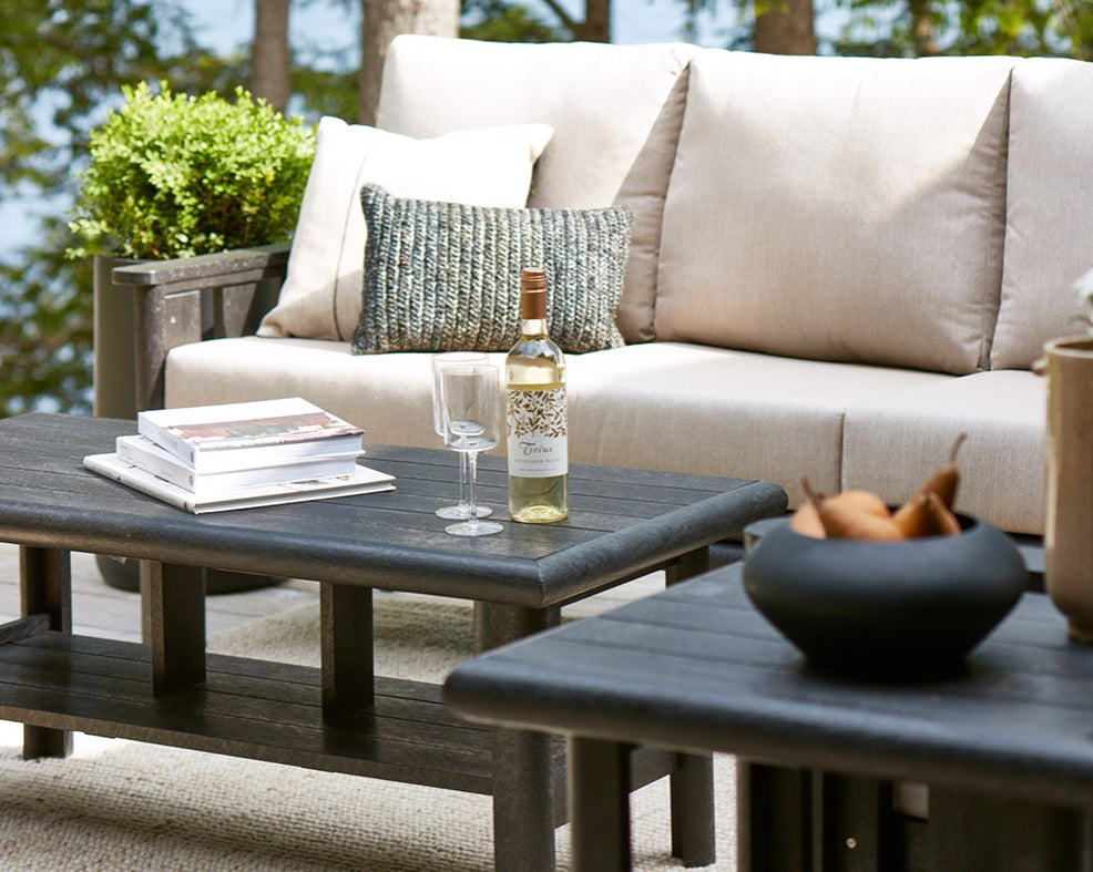 A brown resin couch with tan cushions, a brown resin coffee table and a brown resin end table