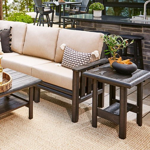A brown resin couch with a tan cushion next to a brown coffee table and a brown end table