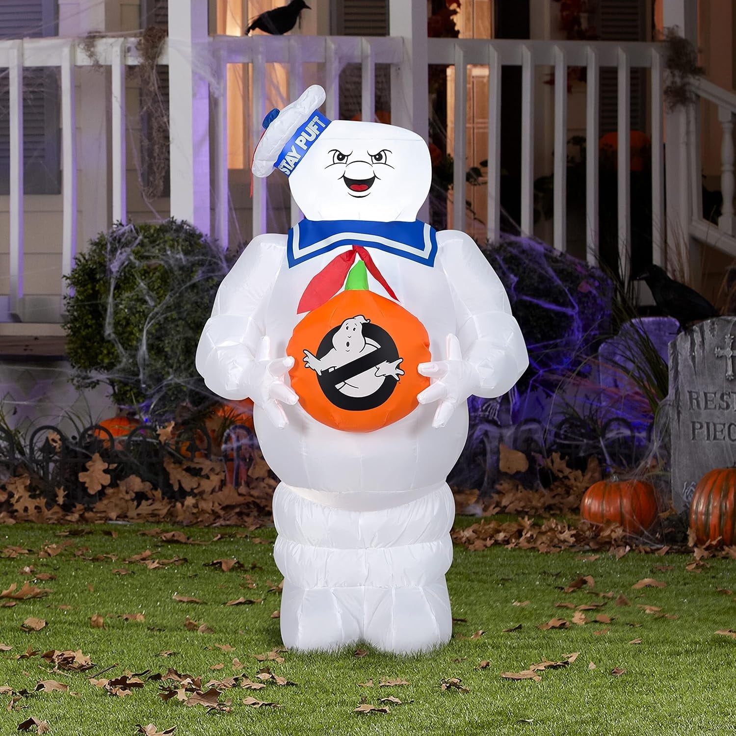 Halloween inflatable shaped like the Stay Puft Marshmallow Man from the movie Ghostbusters. He's holding a pumpkin with the Ghostbusters logo on it.