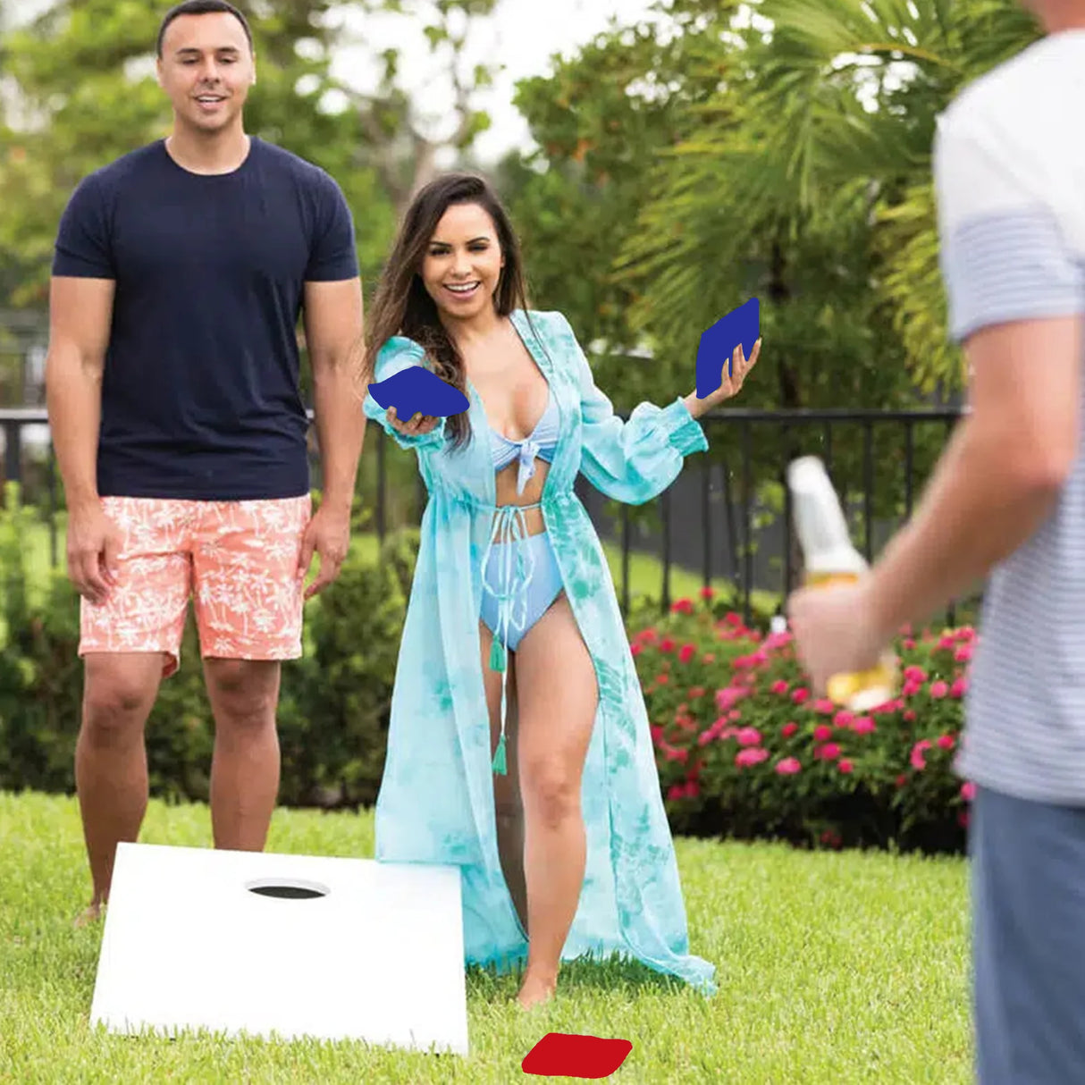 This is a lifestyle image for the cornhole set from Ledge Lounger. This picture shows a woman throwing bean bags at the other board while her teammate cheers her on.