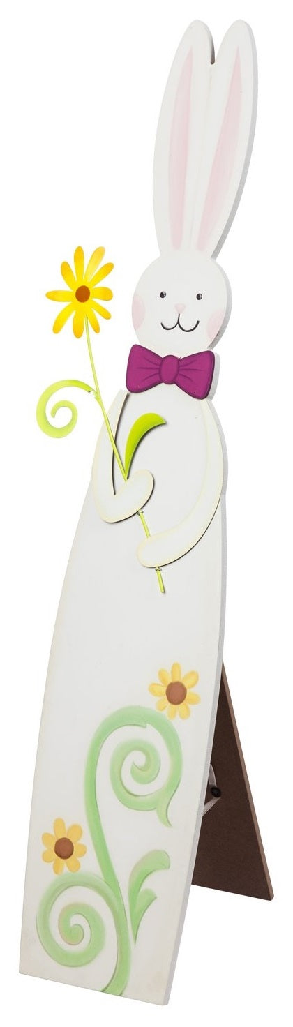 A porch decoration that is shaped like a tall bunny. It's holding a yellow flower and features two yellow flowers and green stems at the base