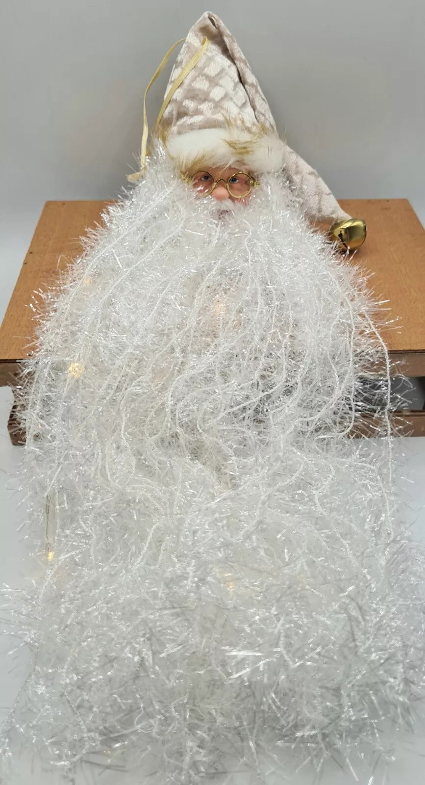 Santa with long white beard ornament. Available in 3 different styles. One Santa is wearing a red stocking cap featuring pine needles, faux berries and a pine cone. One Santa is wearing a red and black buffalo plaid stocking cap. One Santa is wearing a white and gold stocking cap.