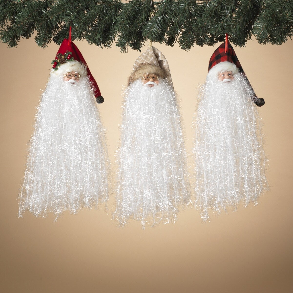 Santa with long white beard ornament. Available in 3 different styles. One Santa is wearing a red stocking cap featuring pine needles, faux berries and a pine cone. One Santa is wearing a red and black buffalo plaid stocking cap. One Santa is wearing a white and gold stocking cap.