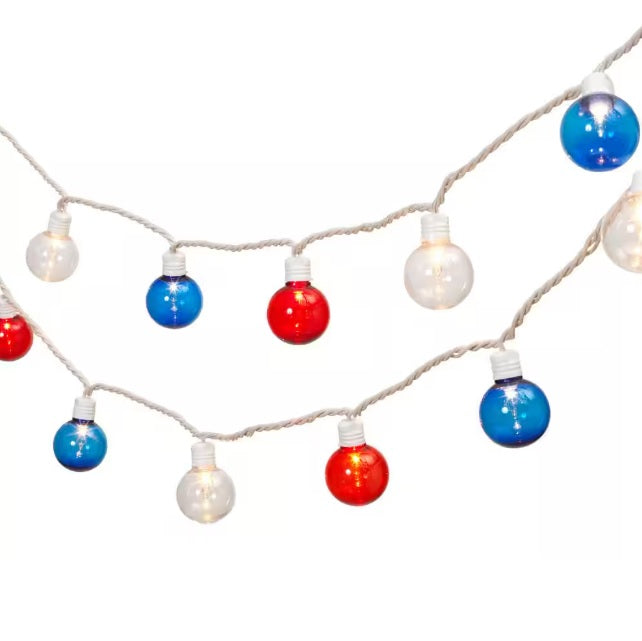A string of red, white and blue globe lights set against a white background.