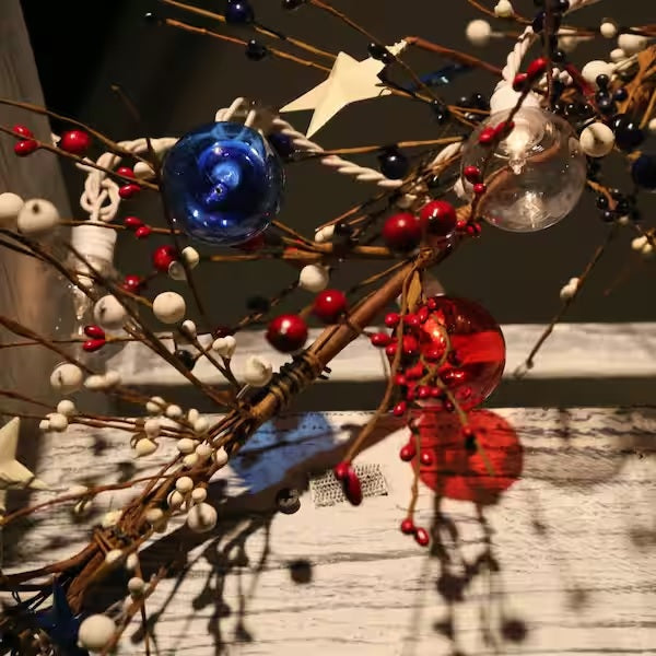 A string of red, white and blue globe lights wrapped around a a decorative plant.