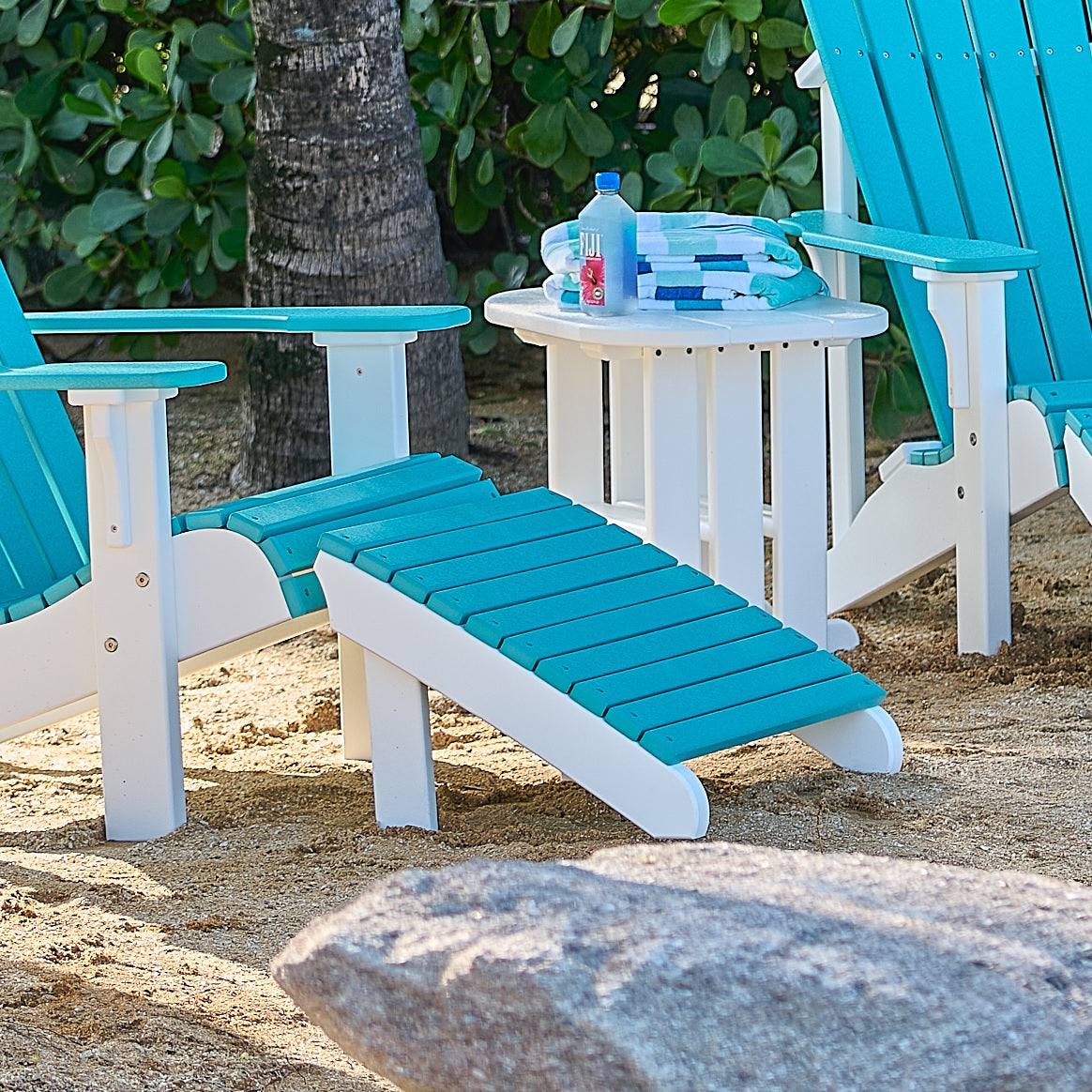 This is the Aruba Blue and White Adirondack footrest in front of a matching Adirondack chair on a beach.