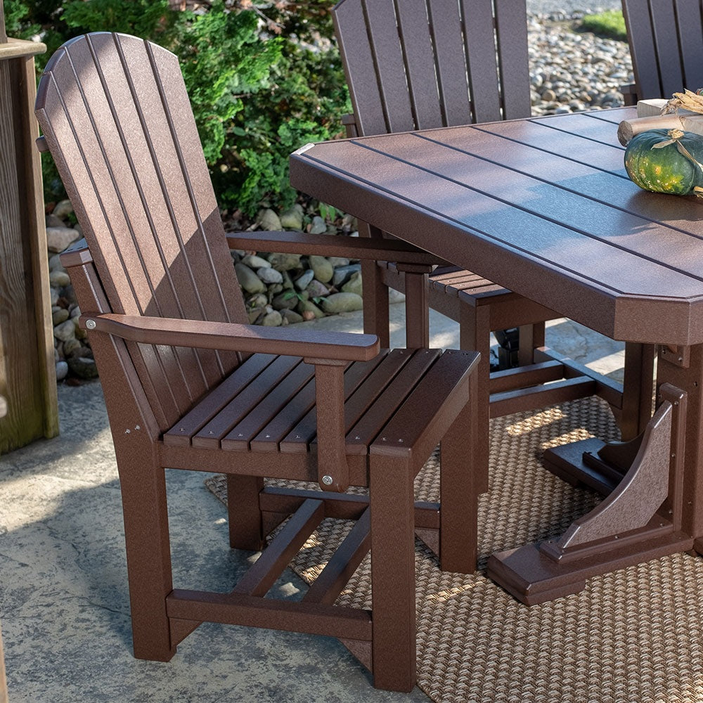 This is a lifestyle image showing the Chestnut Brown colored Adirondack Arm Chair in front of a matching patio dining table.