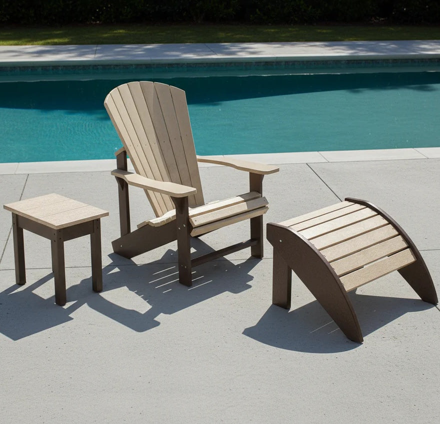 This is a lifestyle image showing this Adirondack chair, ottoman and side table on a cement patio next to a pool on a sunny day.