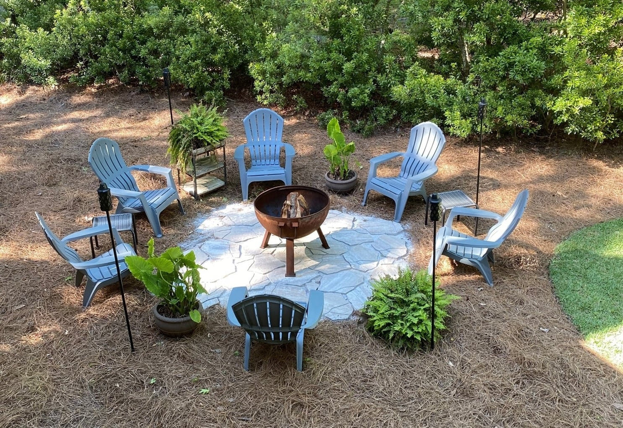 Six blue adirondack chairs in a circle around a campfire.