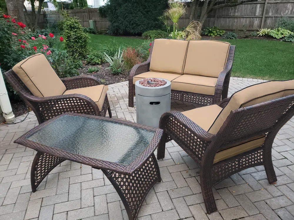 Patio furniture set on a stone patio. The frames are dark brown and the cushions are an orange-ish, tan color.