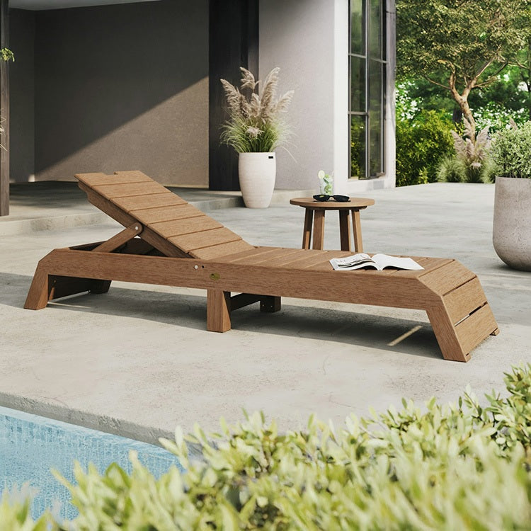 This is a lifestyle image showing the Antique Mahogany colored chaise lounge chair on a concrete patio next to a pool.