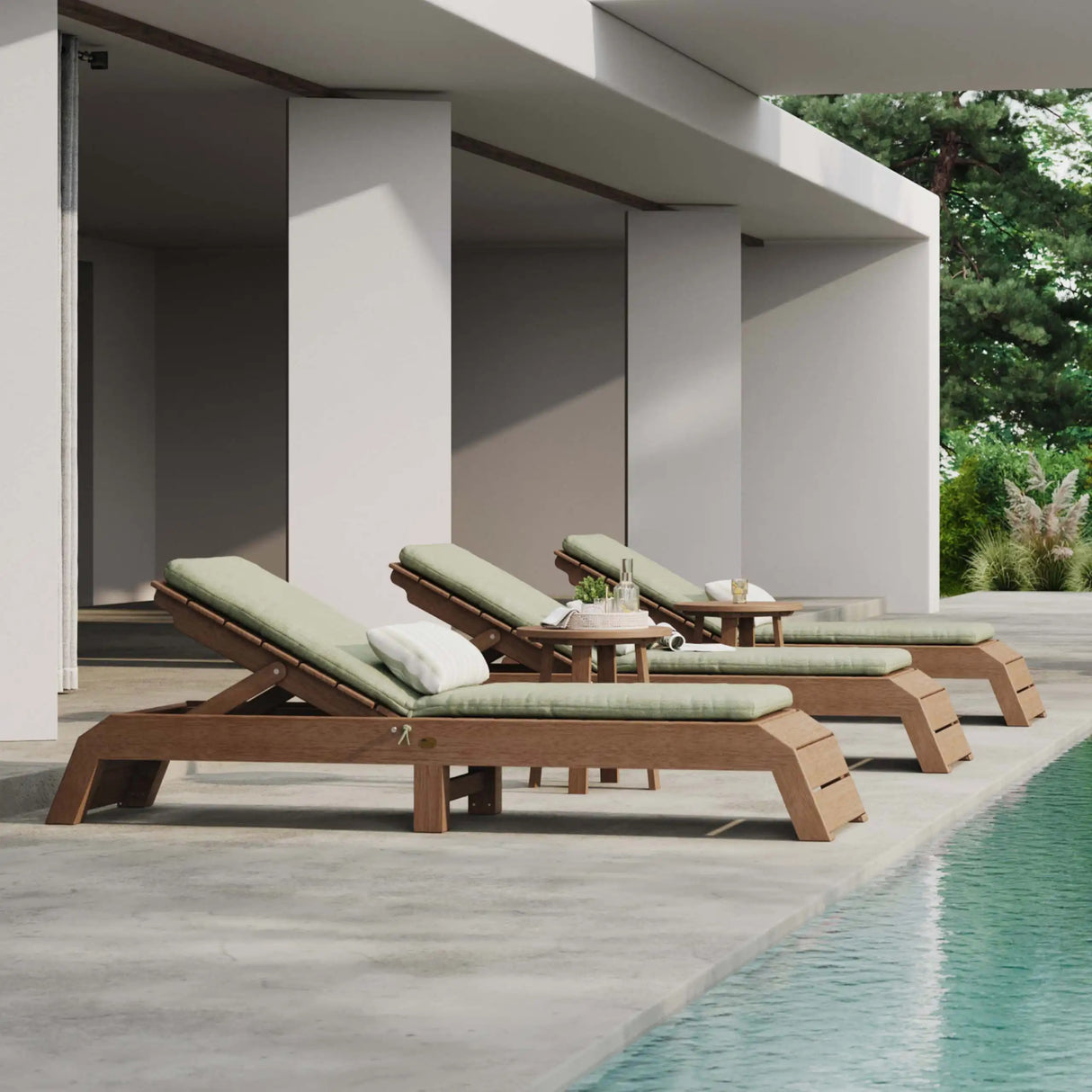 This is a lifestyle image showing three matching Antique Mahogany chaise lounge chairs on a concrete patio in front of a pool. These chairs have light green colored seat cushions on them (which are sold separately).