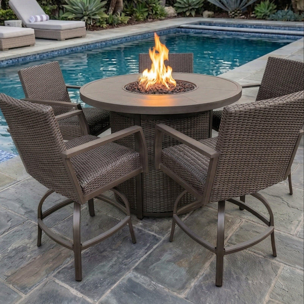 This is a lifestyle image showing these five wicker barstools around a wicker fire pit table on a stone patio next to an inground pool.