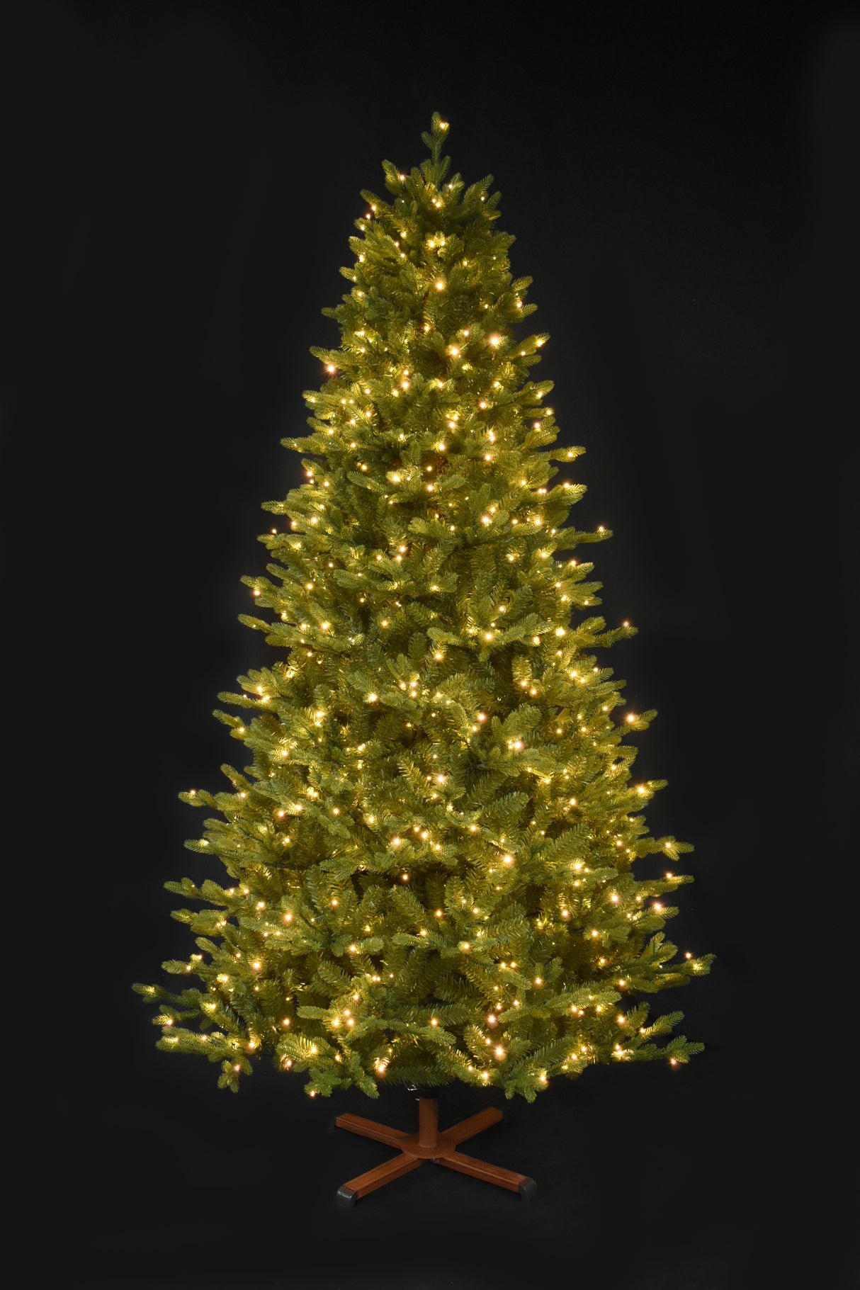 This image shows the tree pre-lit with Warm White Starry Lights. It has a wooden tree stand. This shows the tree on a black background.