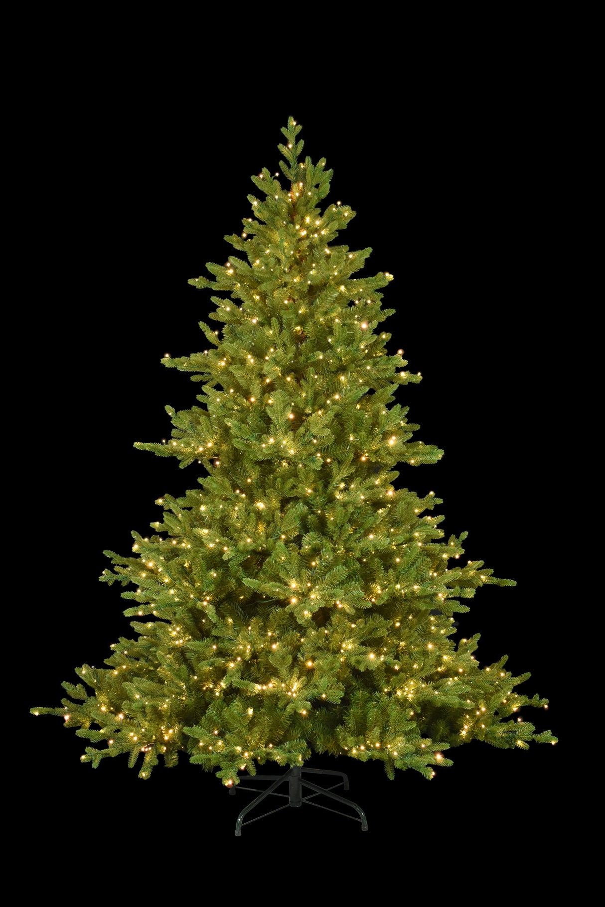 This image shows this specific 7.5 ft. artificial tree pre-lit with Warm White Starry Lights. This tree is up against a black background.