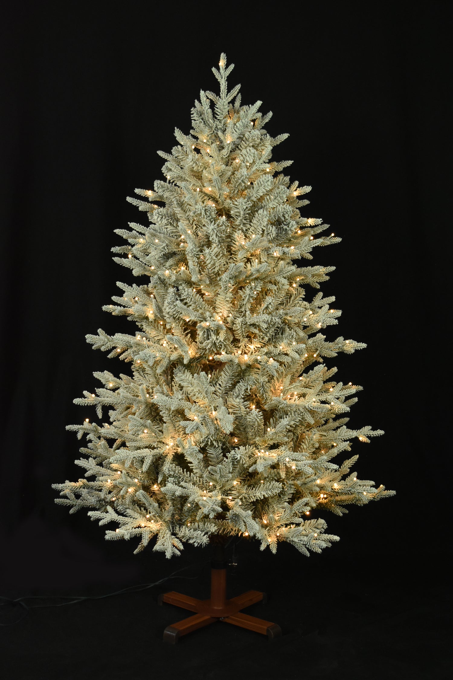 This image shows the flocked Christmas tree pre-lit with Warm White Starry Lights. The tree is up against a black background.