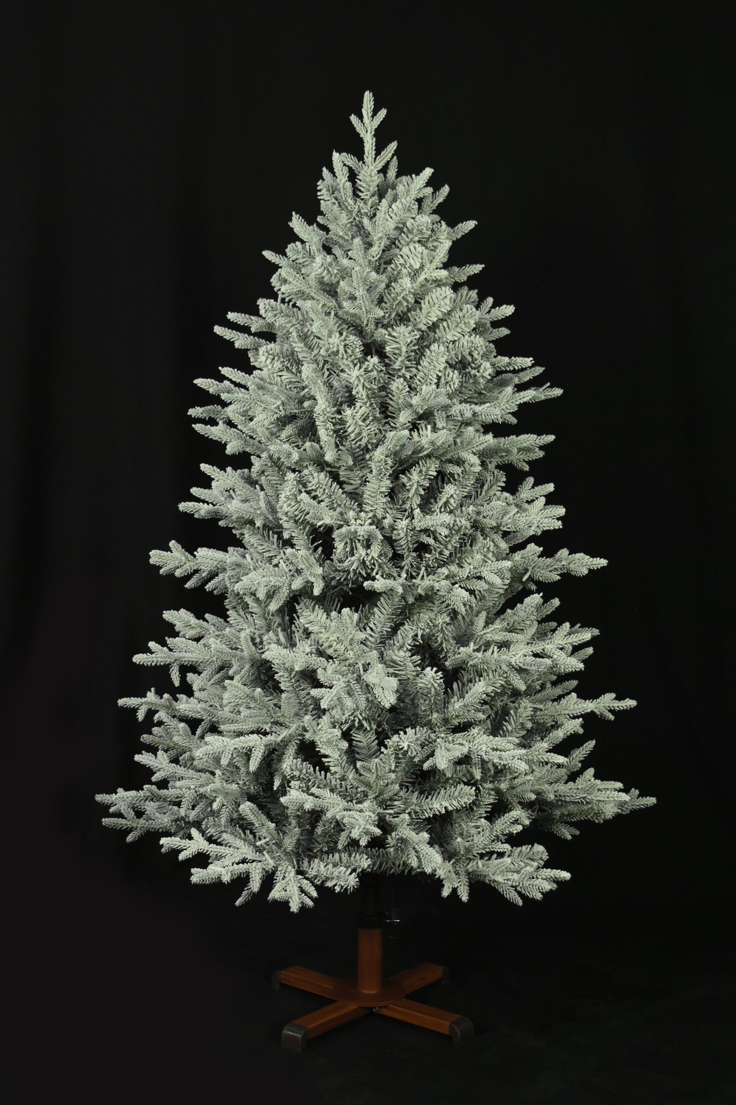 This image shows the flocked Christmas tree with the lights turned off. The tree is up against a black background.