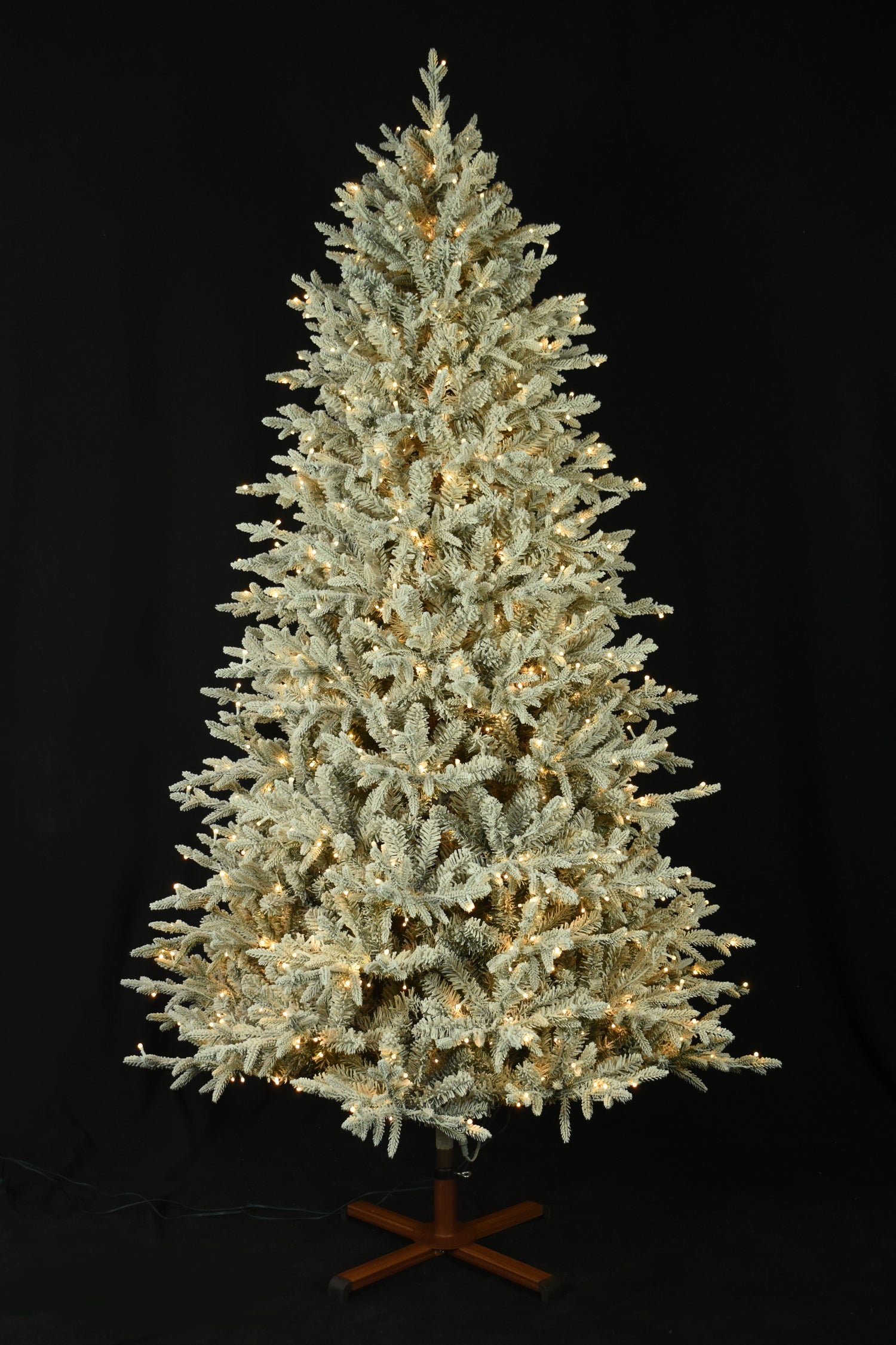 This image shows the flocked Christmas tree pre-lit with Warm White Starry Lights. The tree is up against a black background.