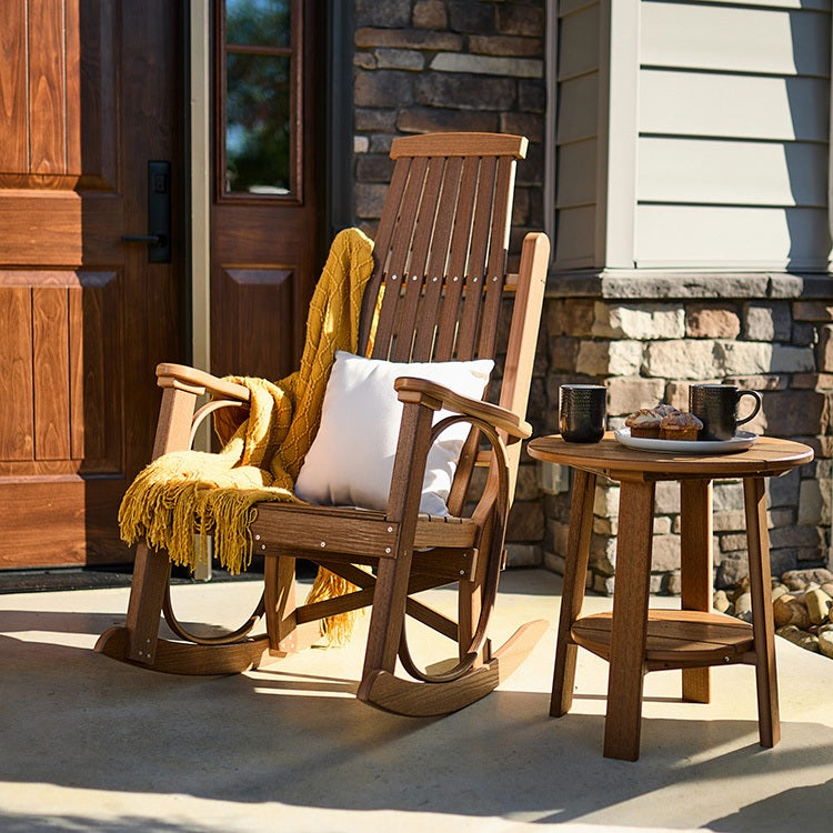 This is a lifestyle image showing an Antique Mahogany colored Grandpa's Rocker Chair next to a matching table on a concrete patio in front of a door.