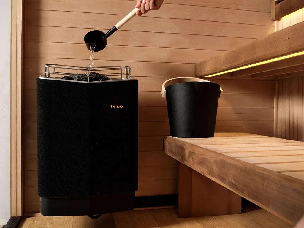 This image shows someone pouring water on the heat source inside the sauna.
