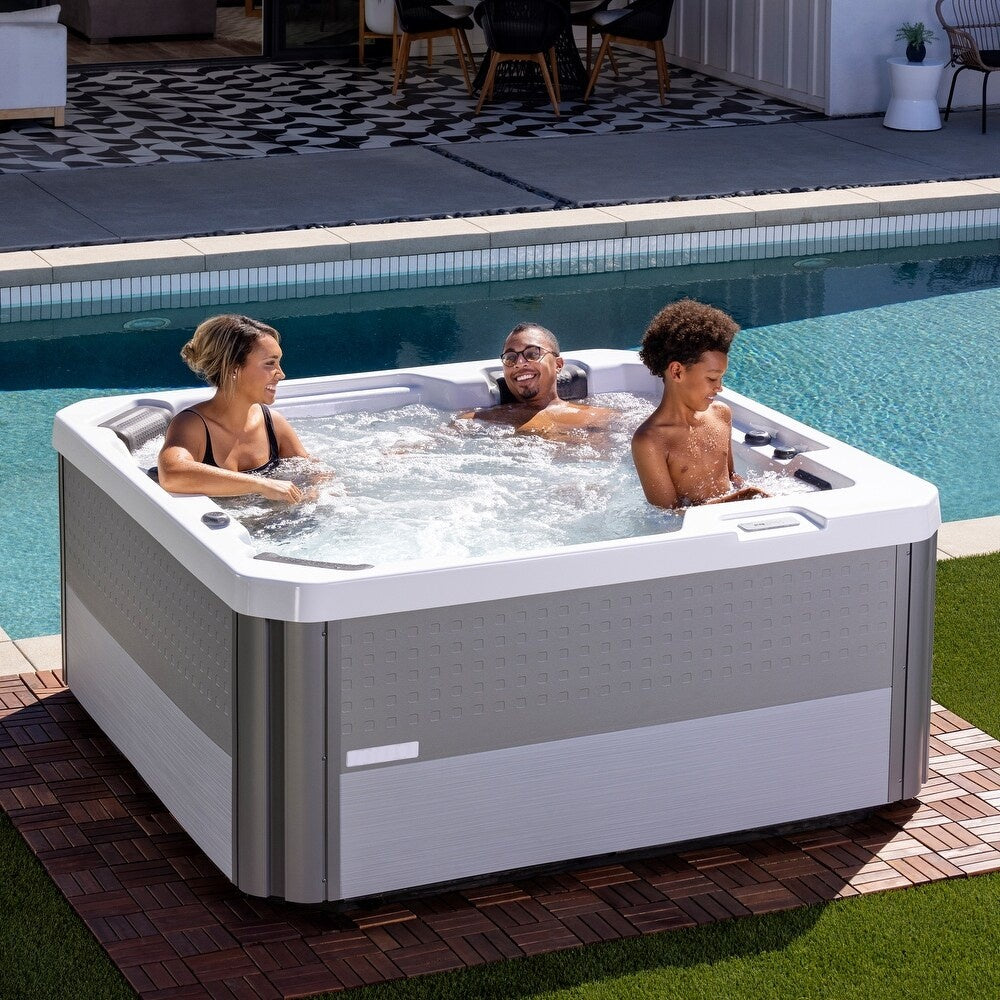 This is a lifestyle image showing a mom, a dad and a son enjoying the jets from the Inspire hot tub in their backyard.