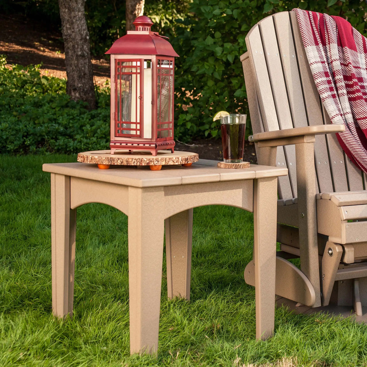 This is a lifestyle image showing the Weatherwood colored end table with a matching glider chair next to it.
